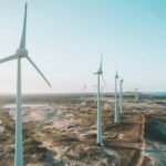 a row of wind turbines next to the ocean